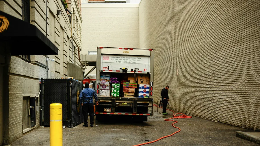 A delivery being unloaded by hand in a narrow alley